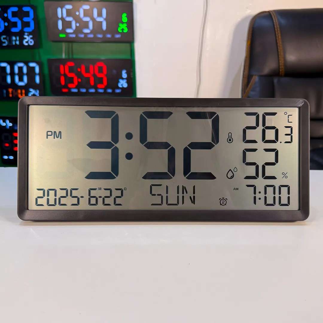 Large LCD digital clock placed on a tabletop, displaying time, temperature, humidity, day, and date.